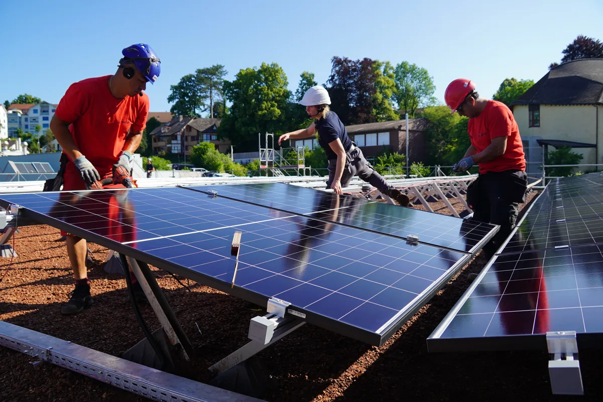 Drei Personen montieren Solarpanels auf das Dach der Neubauten der Ara in Wetzikon.